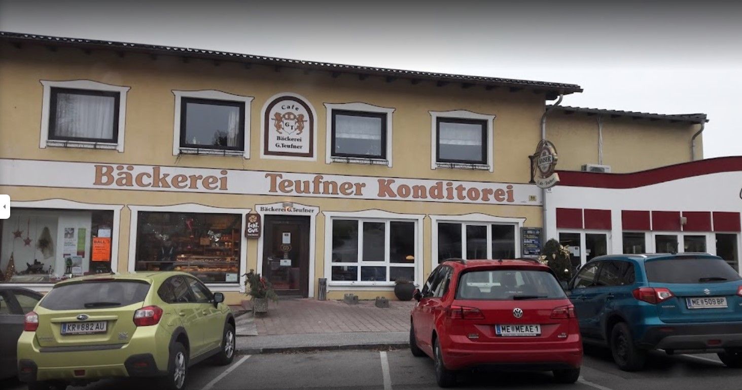 Exteriérový pohľad na pekáreň Teufner so zaparkovanými autami pred ňou.