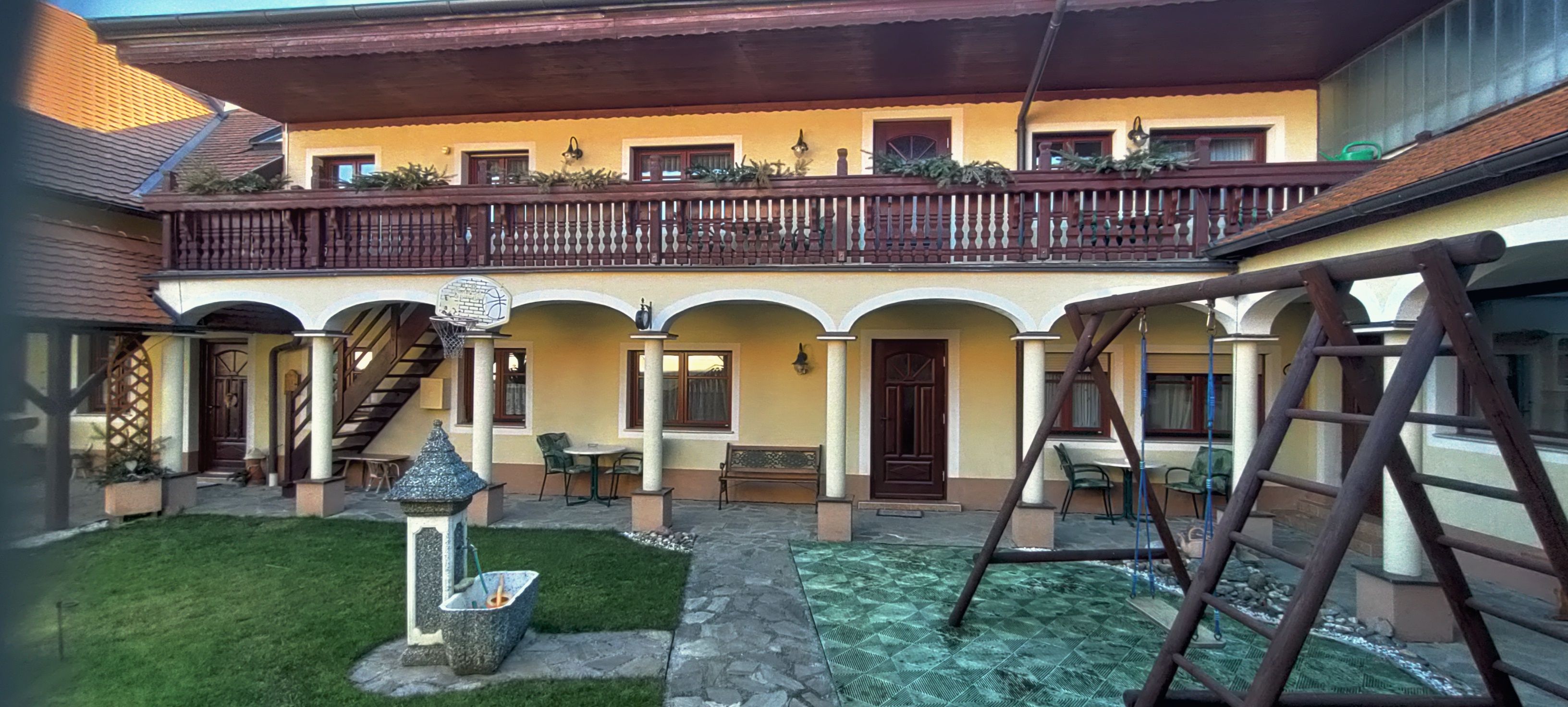 Vnútorné nádvorie s arkádami, balkónom, hojdačkou a fontánou.