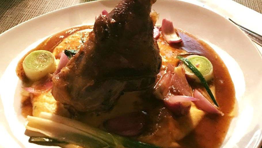 Tanier s mäsovým pokrmom podávaným na zemiakovej kaši s hnedou omáčkou a zeleninou.