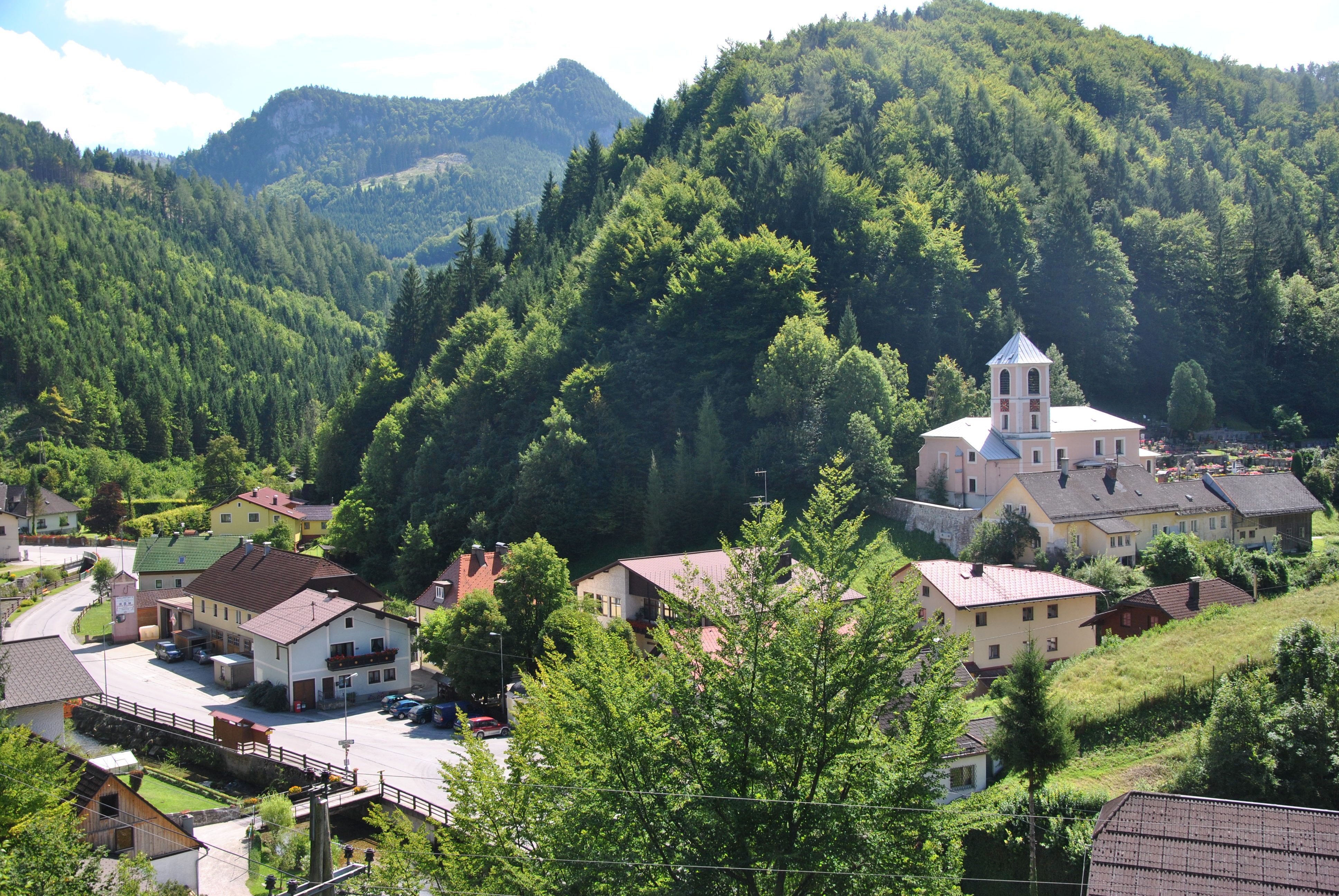 Malá dedinka v zelenej horskej krajine s kostolom a domami.