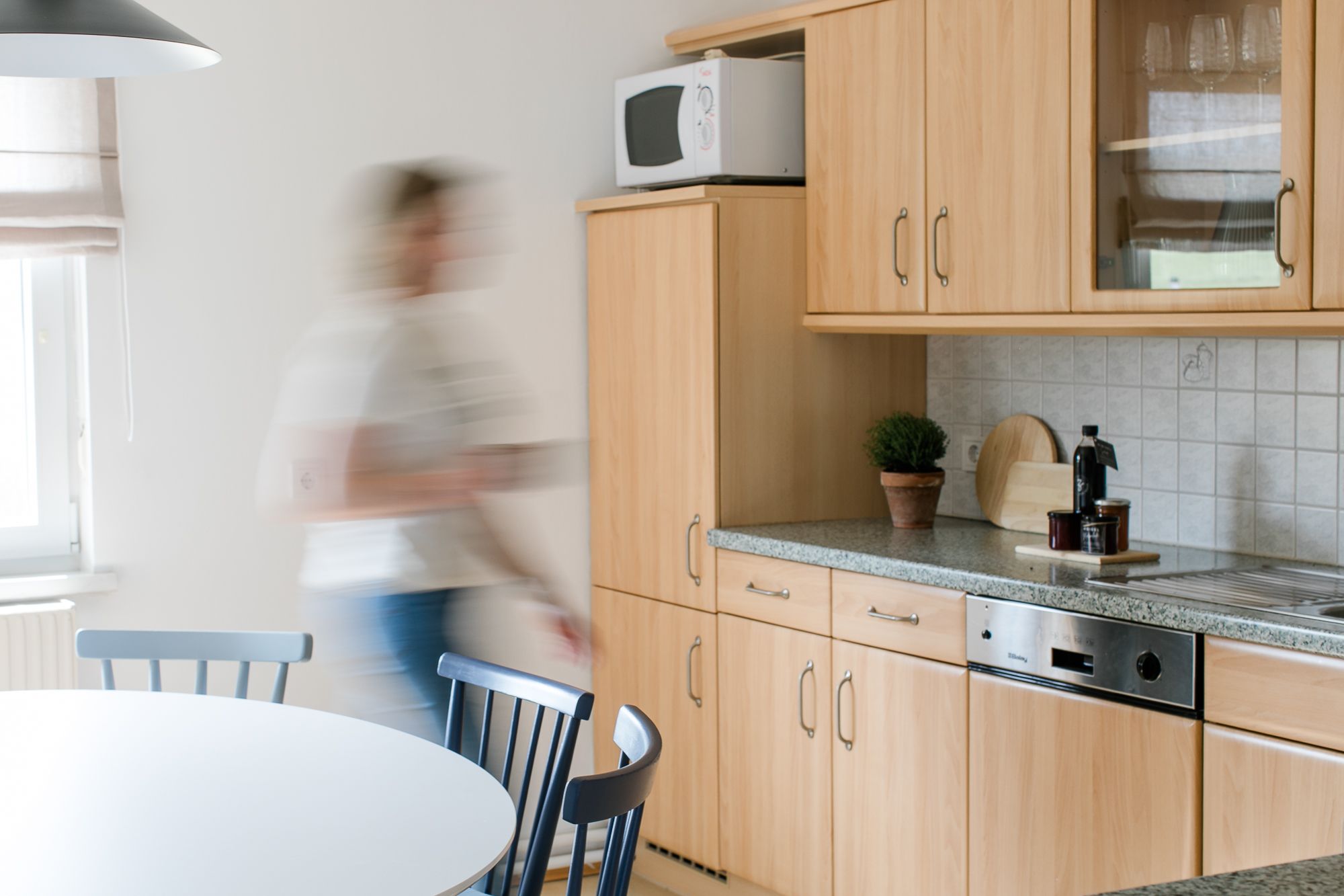 Moderná kuchyňa s dreveným nábytkom a jednou osobou v pohybe.