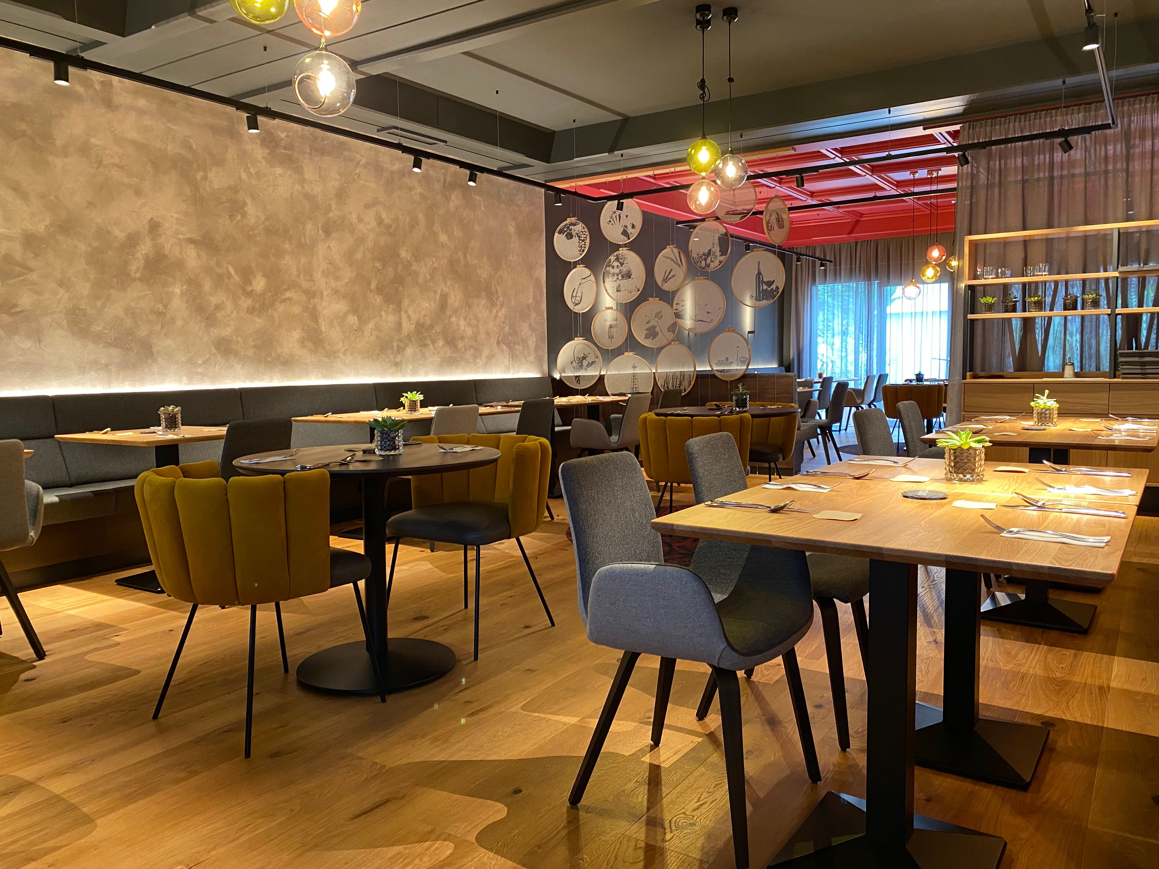 Moderná reštaurácia so štýlovým nábytkom, drevenými stolmi a pohodlnými stoličkami.