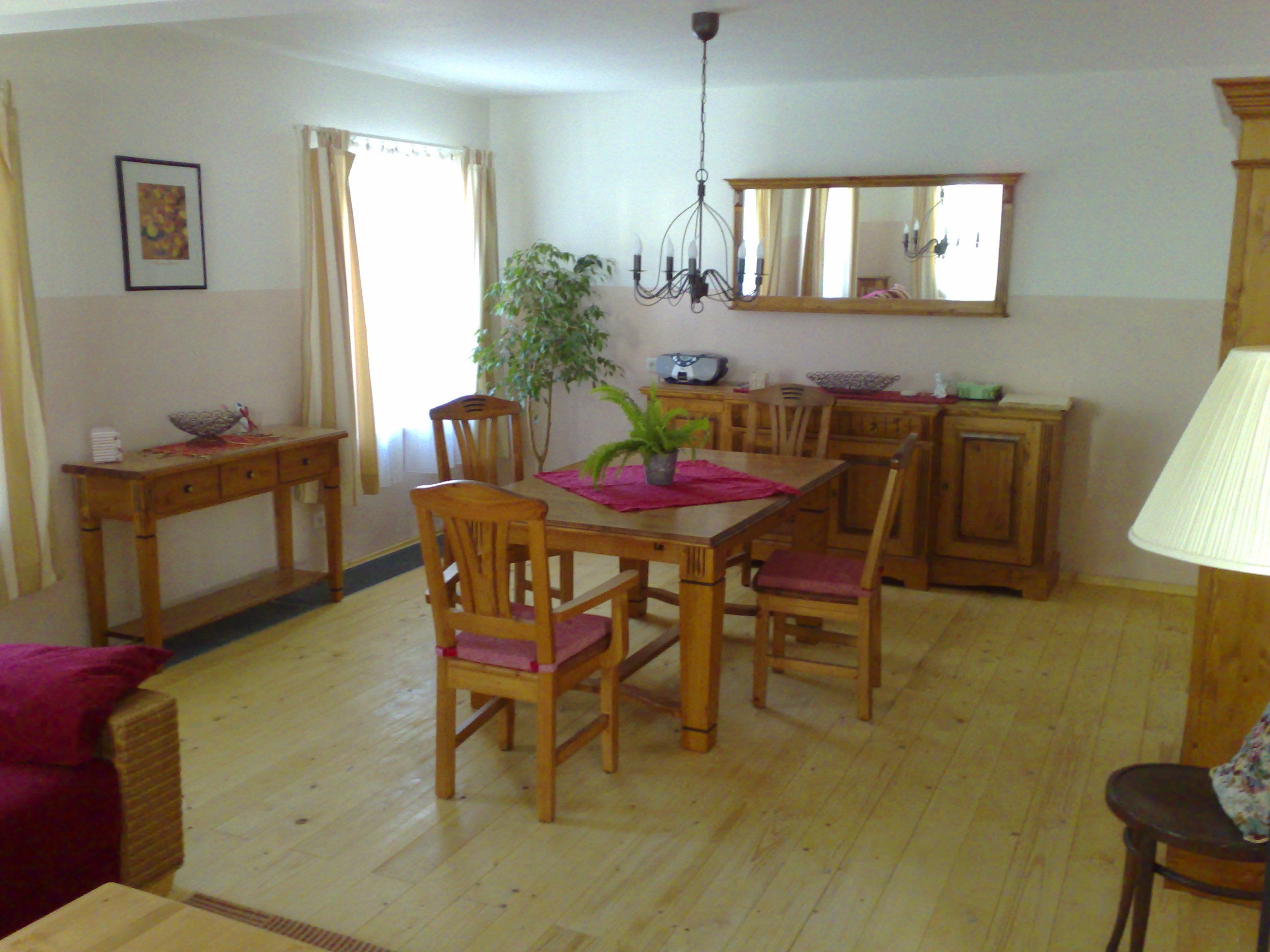 Útulná obývacia izba s dreveným nábytkom, jedálenským stolom, stoličkami a rastlinami.