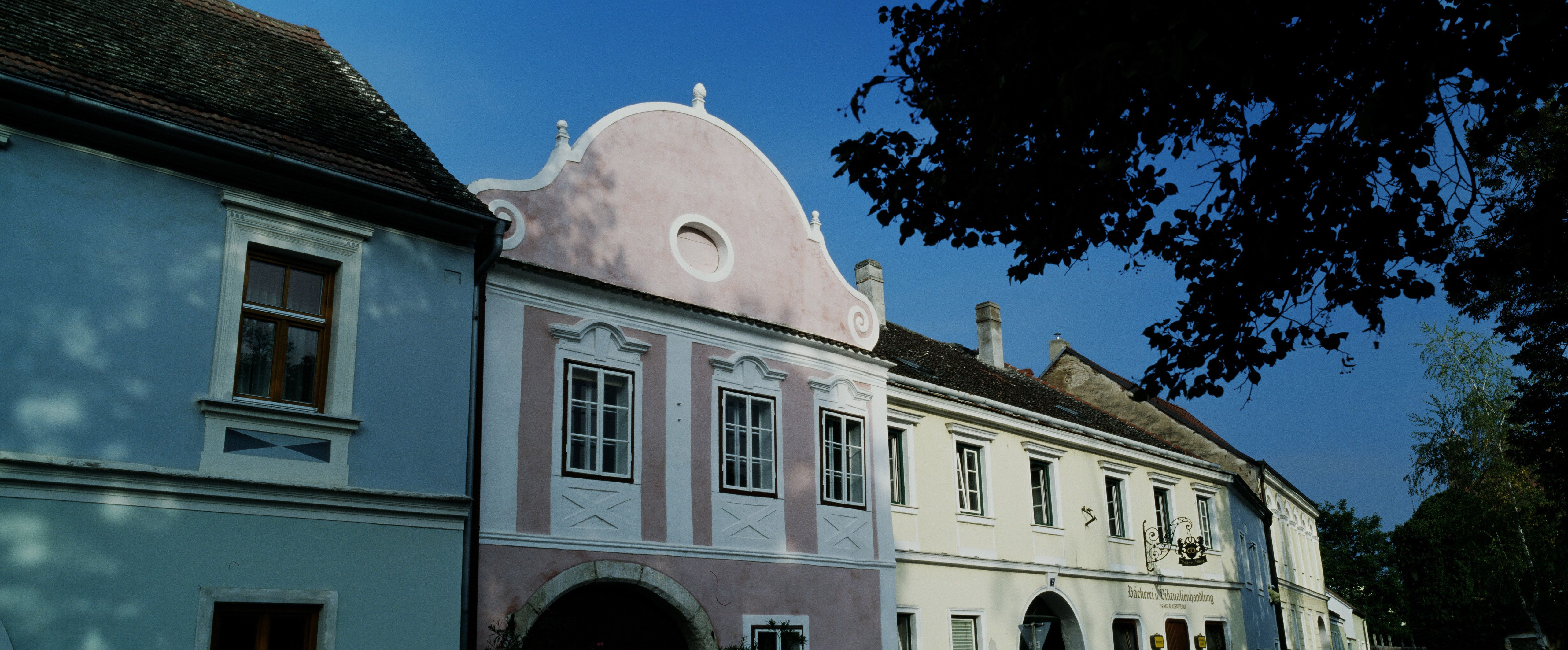 Historické budovy v Hadersdorfe-Kammerne s modrými a ružovými fasádami.