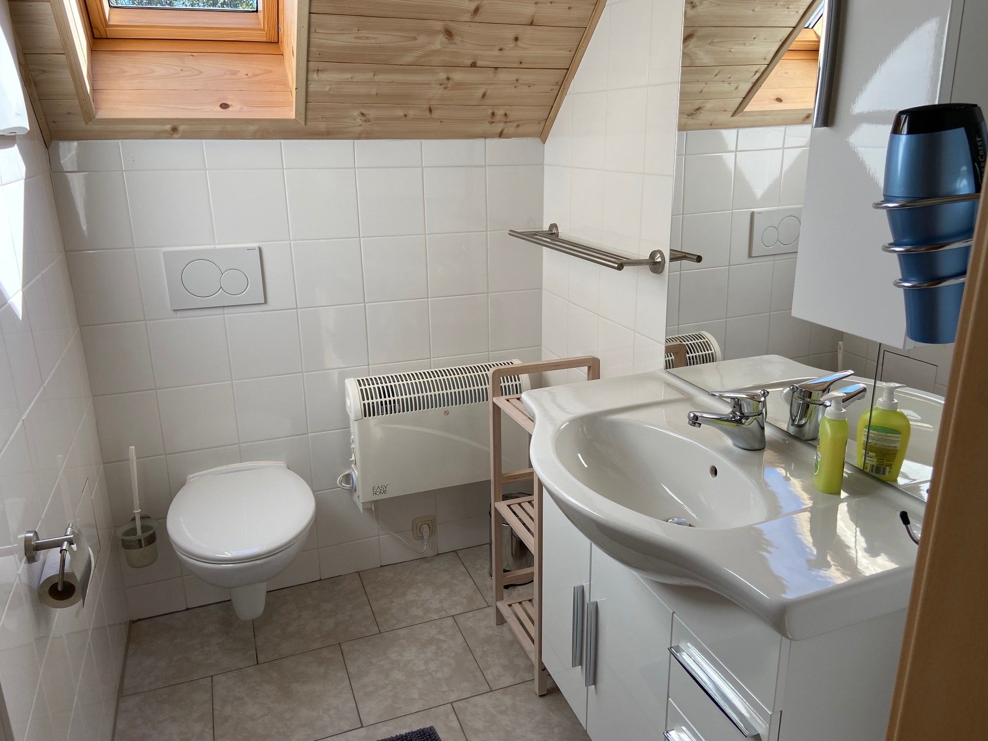 Moderná kúpeľňa so strešným oknom, umývadlom, WC a držiakom na uteráky.