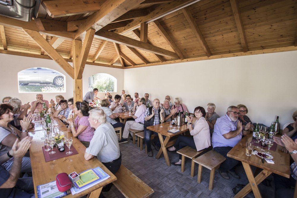 Ľudia sedia pri drevených stoloch vo vinárni a klebetia.