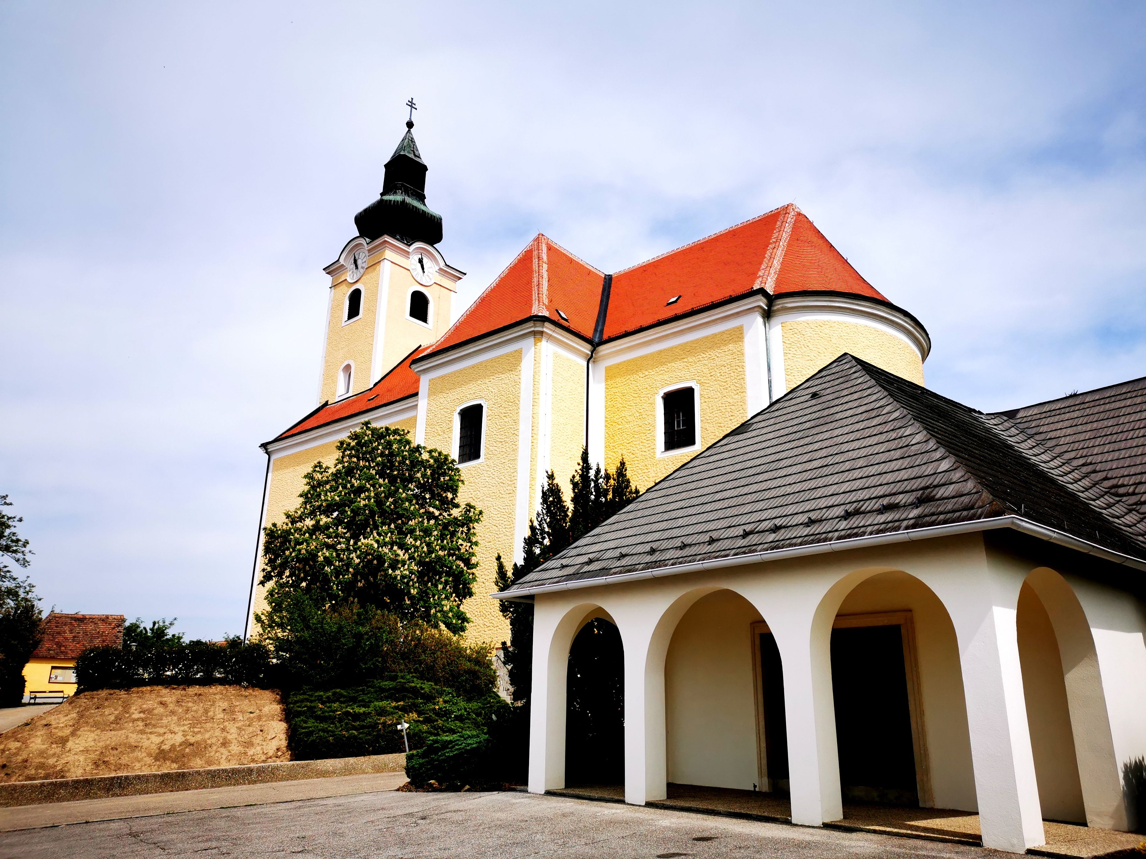 Farský kostol svätého Mikuláša v Röschitzi so žltou fasádou a červenou strechou.