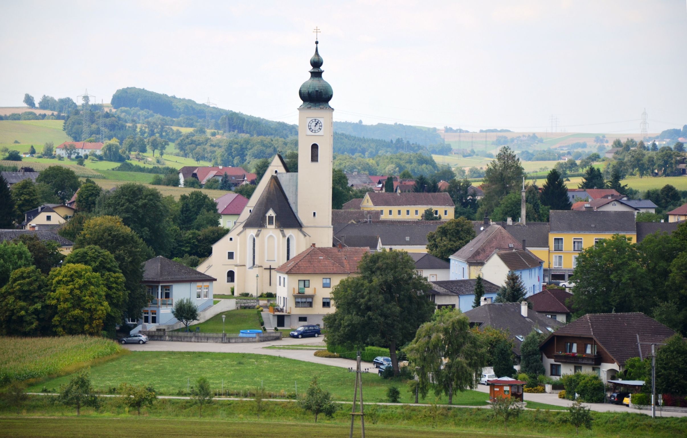 Pohľad na trhové mestečko Ruprechtshofen s kostolom a okolitými domami vo vidieckej krajine.