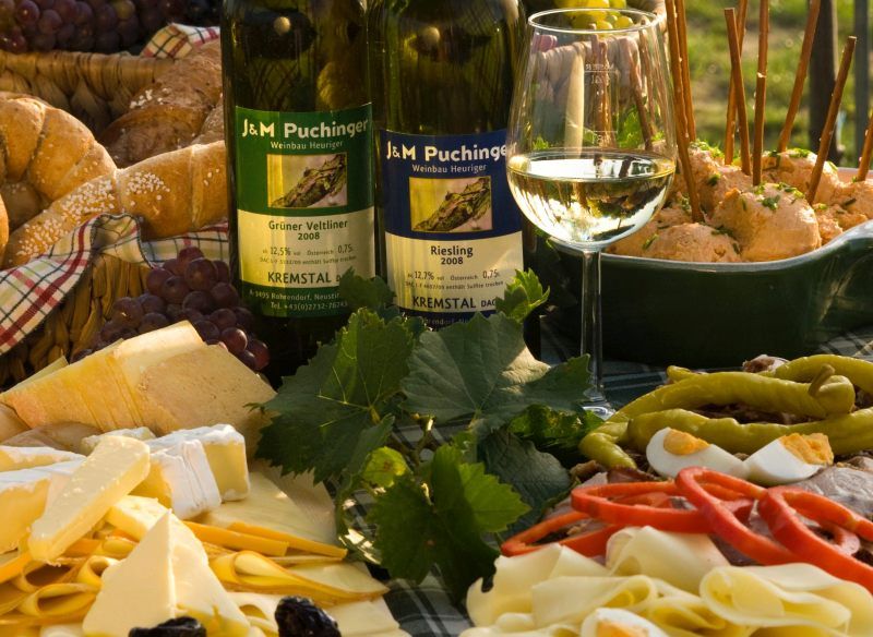 Občerstvenie Heurigen s vínom, syrom, chlebom a údeninami na stole.