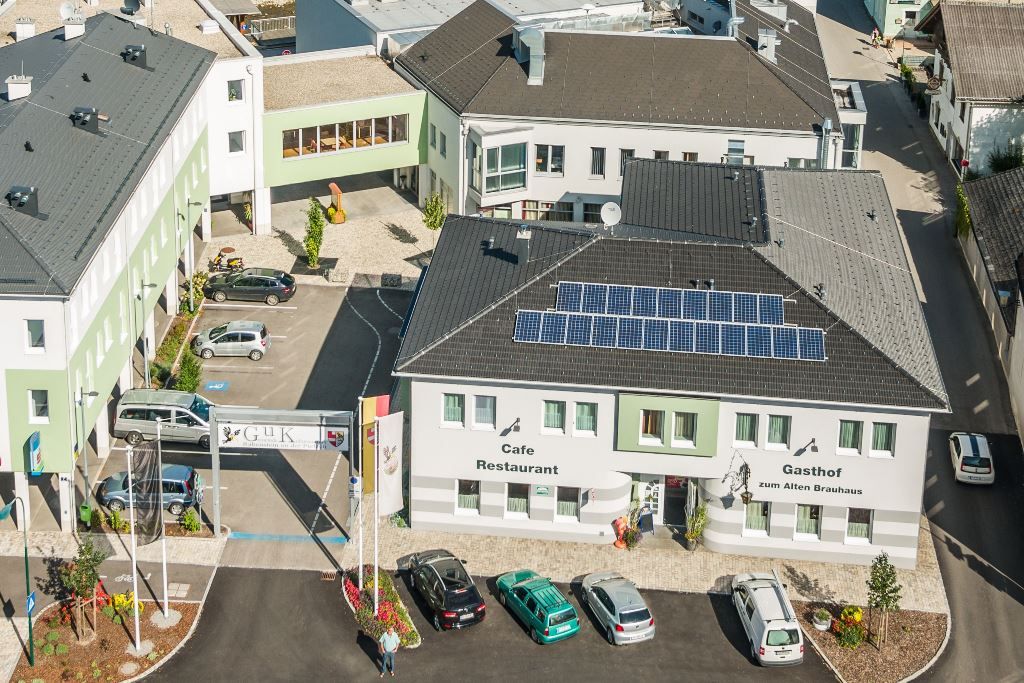 Letecký pohľad na komplex budov s reštauráciou Gasthof zum Alten Brauhaus, solárnymi panelmi na streche a niekoľkými zaparkovanými autami.