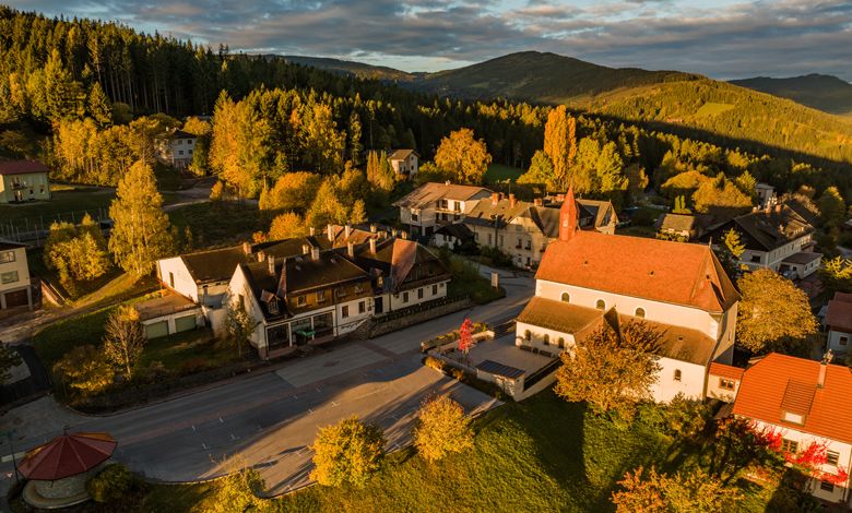 Letecký pohľad na St. Corona am Wechsel s kostolom a okolitými budovami v jesennej krajine.