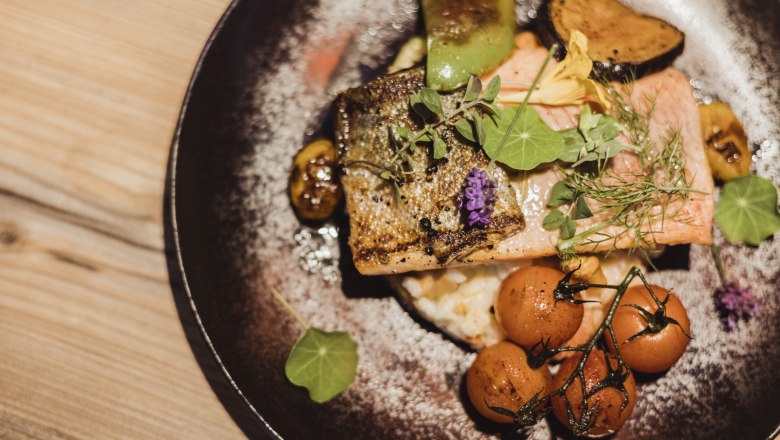 Filet z lososa na tanieri s rizotom z grammelov so zeleninou a bylinkami.