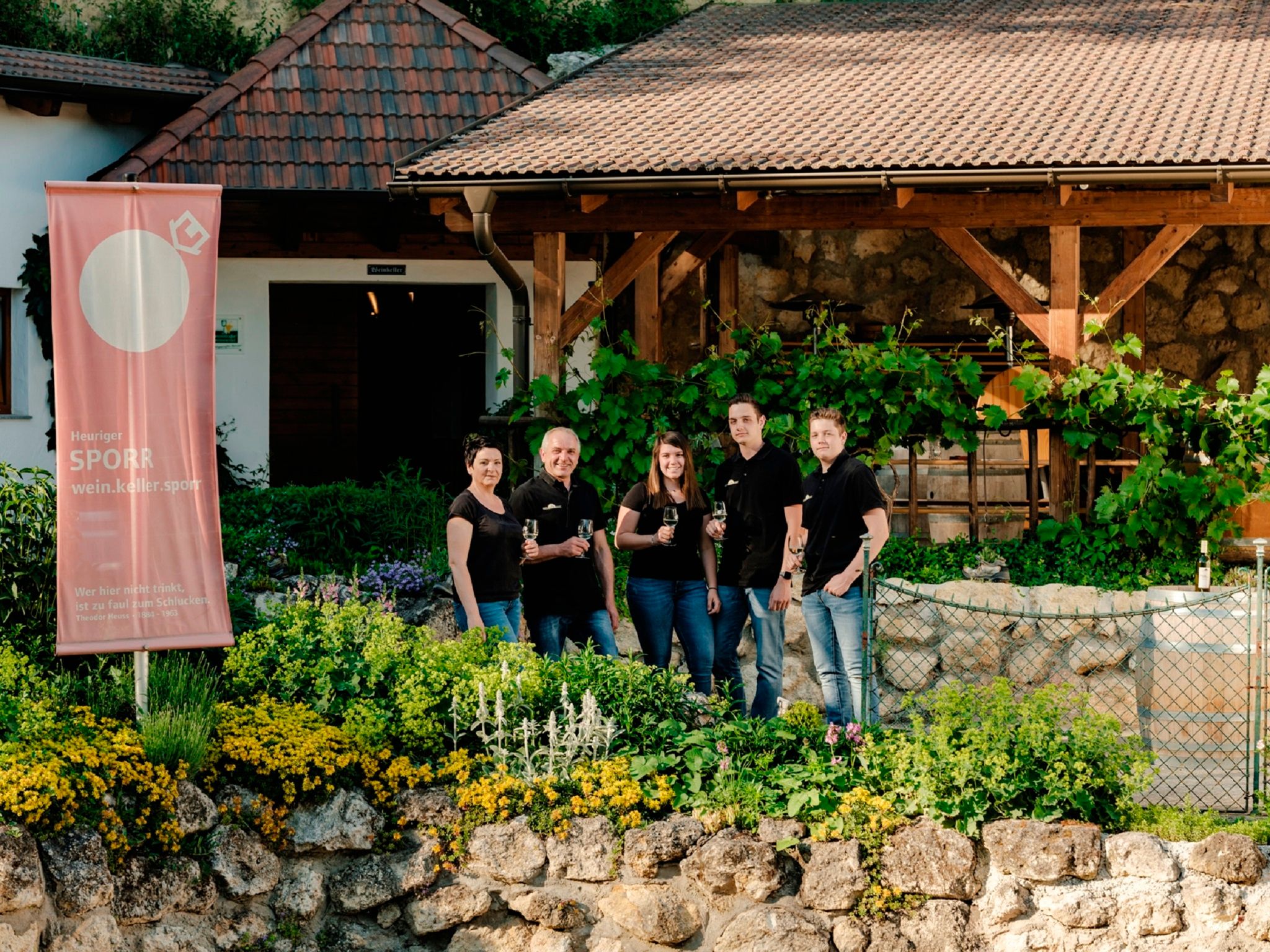 Skupina piatich ľudí pred vinárstvom s transparentom Sporr.