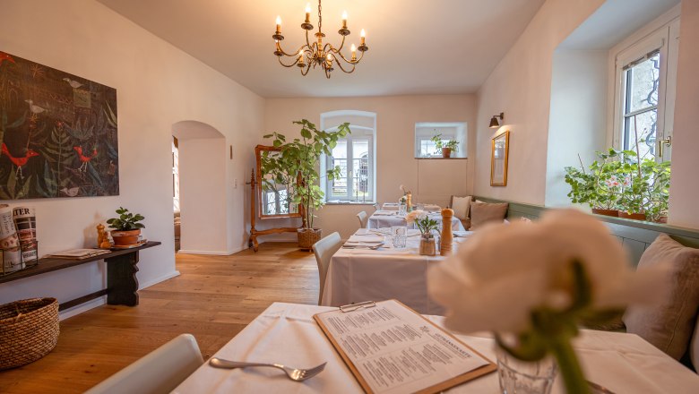 &Uacute;tuln&aacute; re&scaron;taur&aacute;cia s drevenou podlahou, bielymi obrusmi a rastlinami.