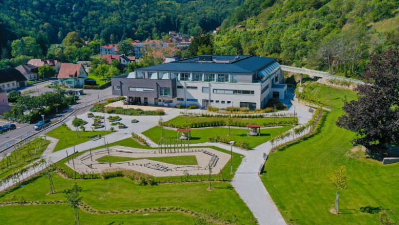 Leteck&yacute; pohľad na modern&uacute; budovu so z&aacute;hradou, obklopen&uacute; zelen&yacute;mi kopcami.