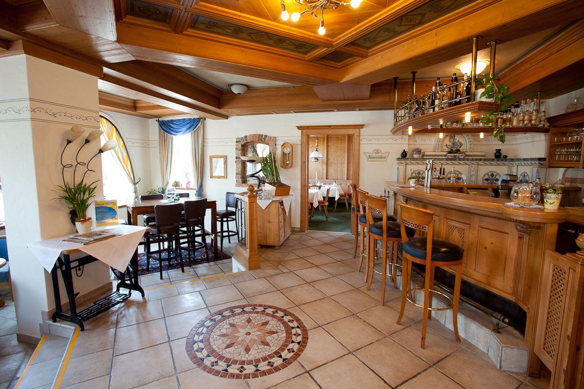 Útulný hotelový bar s dreveným nábytkom a dekoratívnou dlážkou.