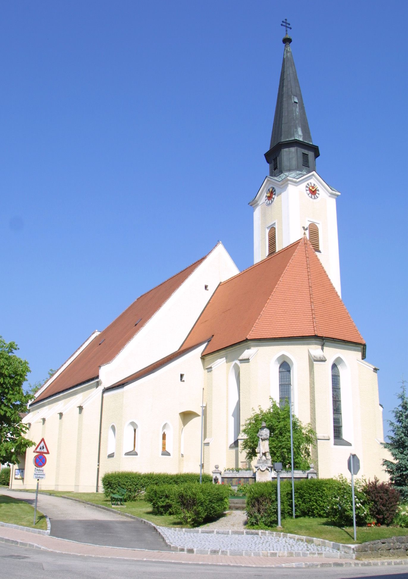 Kostol v Hürme so špicatou vežou a červenou strechou na pozadí modrej oblohy.
