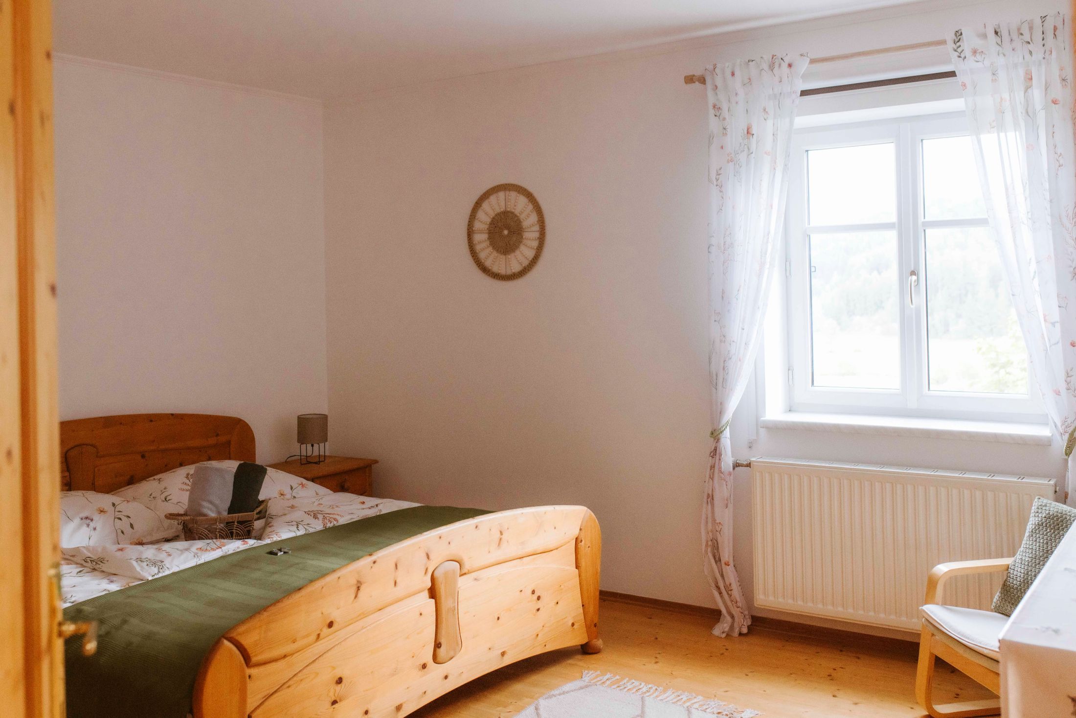 Útulná dvojlôžková izba s dreveným nábytkom a oknom so závesmi.