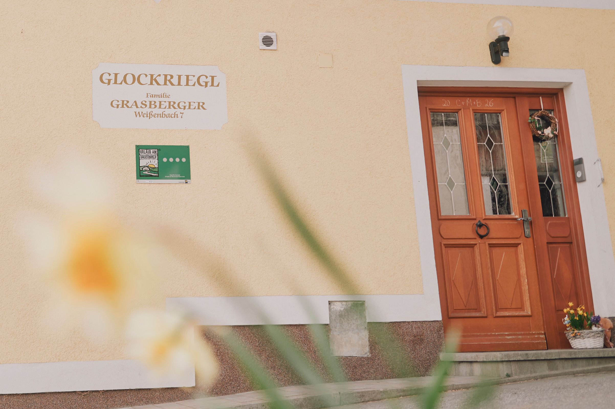 Vchod do domu s drevenými dverami a nápisom "Glockriegl" na stene.