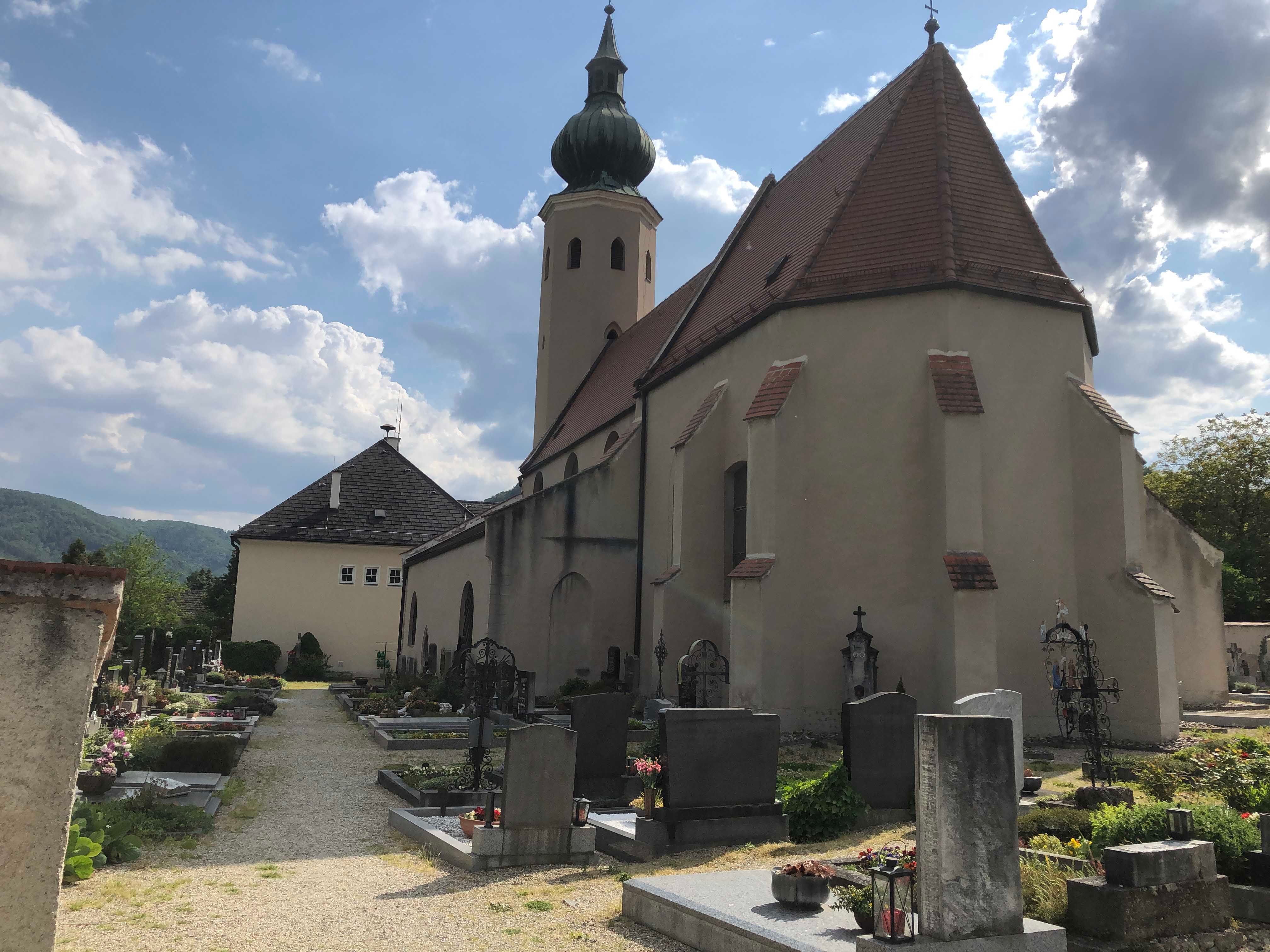 Kostol na námestí Aggsbach Markt s cintorínom v popredí.