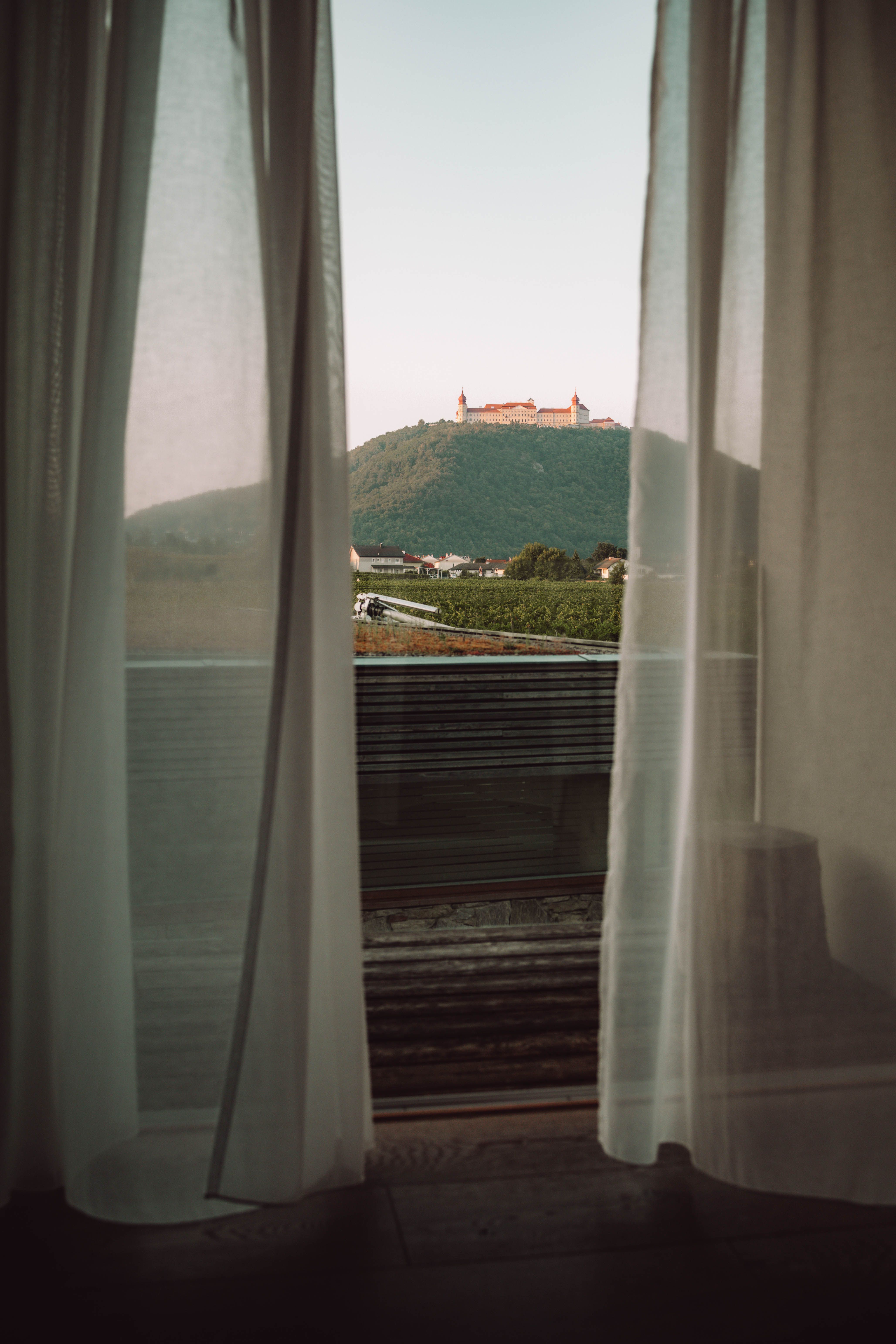 Exteriérový pohľad na vinárstvo a hotel MALAT s modernou architektúrou a vozidlom v popredí.