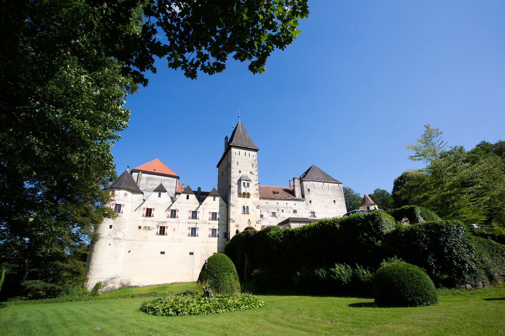 Hrad Feistritz s modrou oblohou a zelenou krajinou.