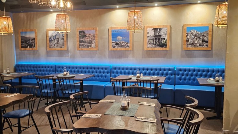 Blue armchairs and laid tables inside the restaurant, © Restaurant athen