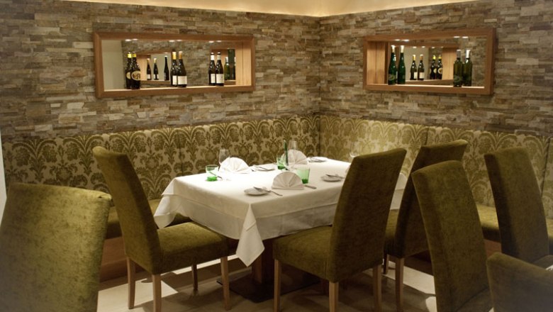 Elegantn&aacute; re&scaron;taur&aacute;cia s prestret&yacute;m stolom a zelen&yacute;mi stoličkami.