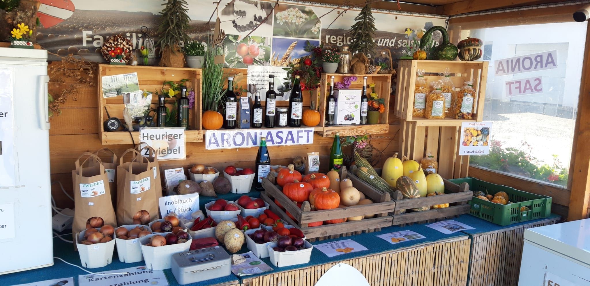 Stánok s regionálnymi výrobkami, ako sú tekvice, cibuľa a aróniový džús.