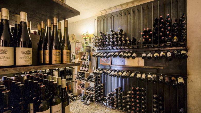Vínna pivnica s policami plnými úhľadne uložených fliaš vína.