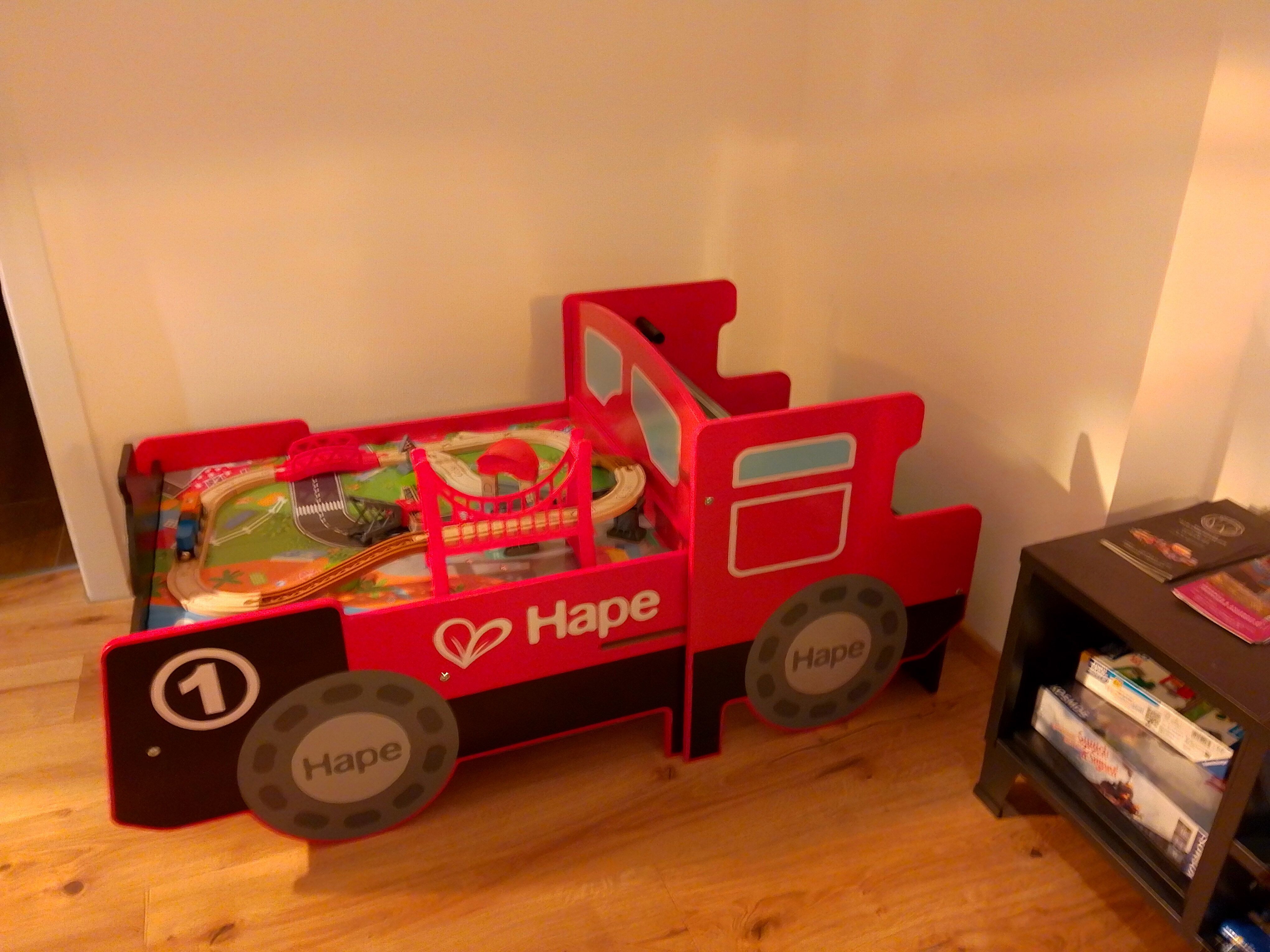 Červená hračkárska posteľ v tvare lokomotívy s hračkárskou železnicou.