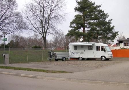 Karavan na pozemku vedľa stromu a plota.