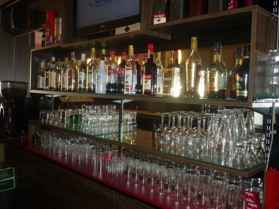 Polica s fľašami a pohármi v bare.