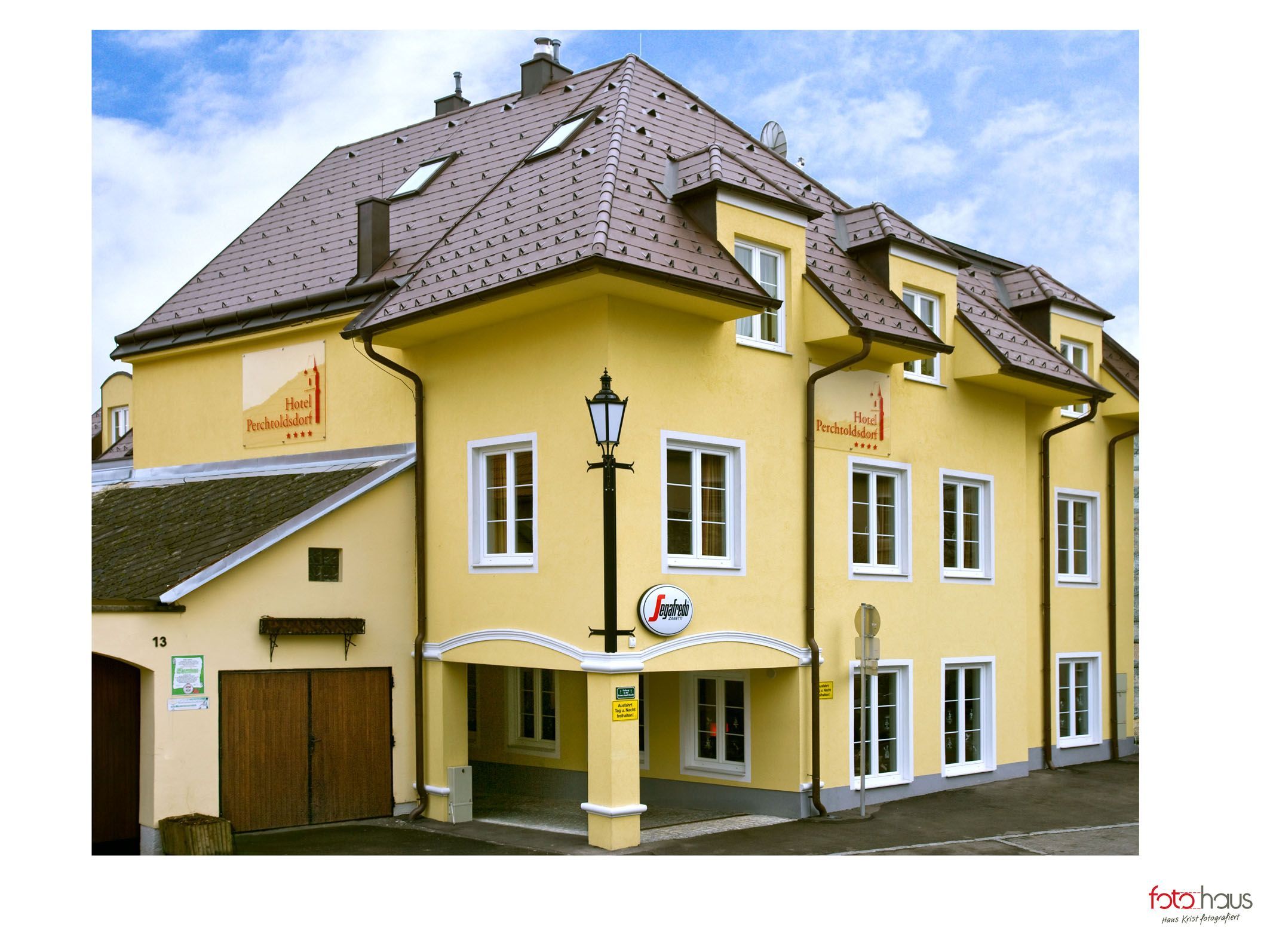 Žltá budova hotela s niekoľkými oknami a nápisom "Hotel Perchtoldsdorf".