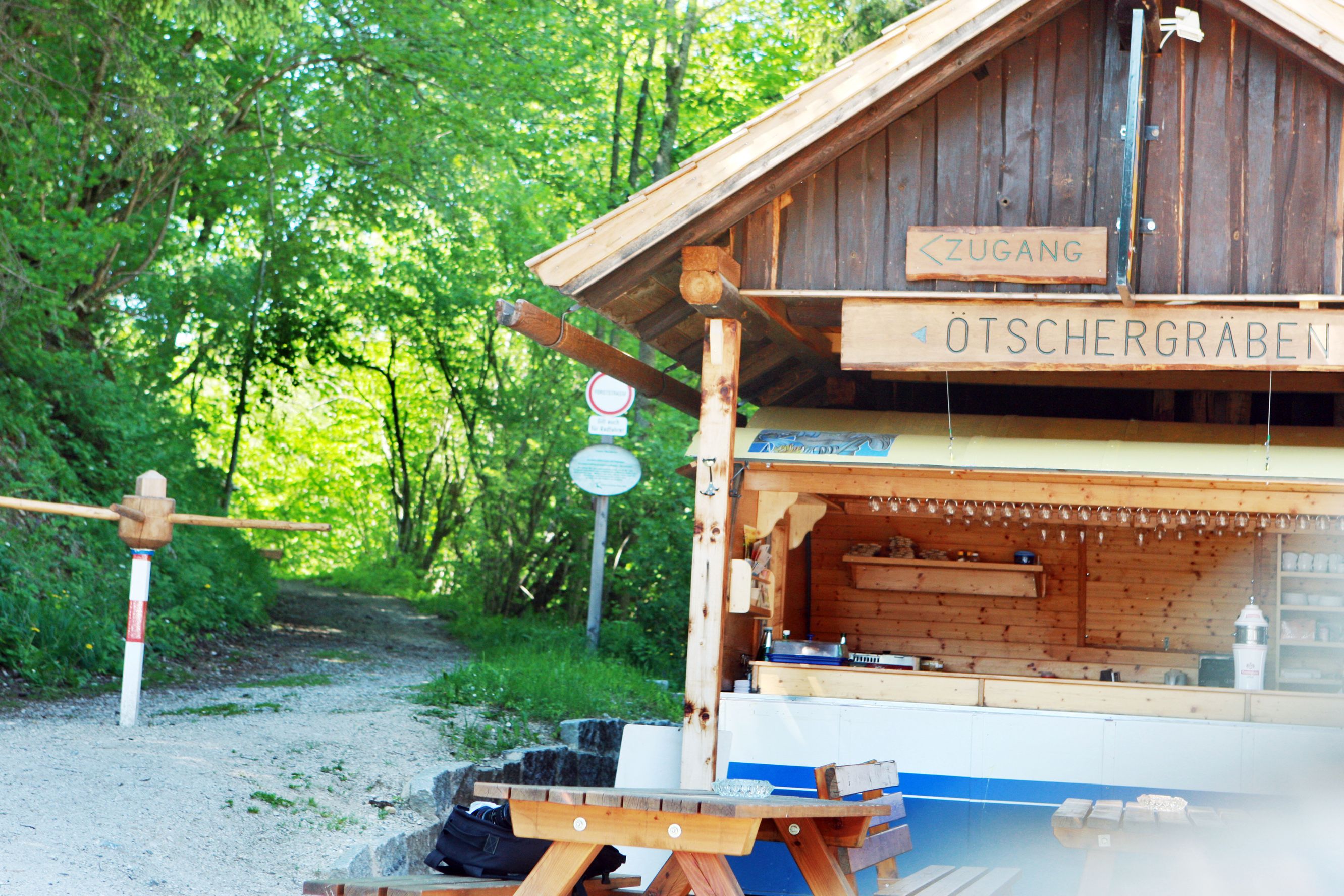 Drevená chata s nápisom "Ötschergräben" a lesnou cestou v pozadí.