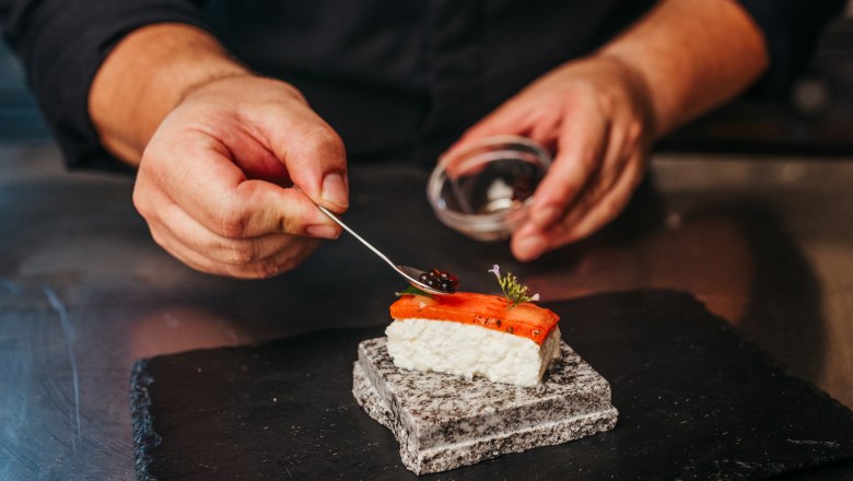 Šéfkuchár zdobí kúsok sushi kaviárom na kameni.
