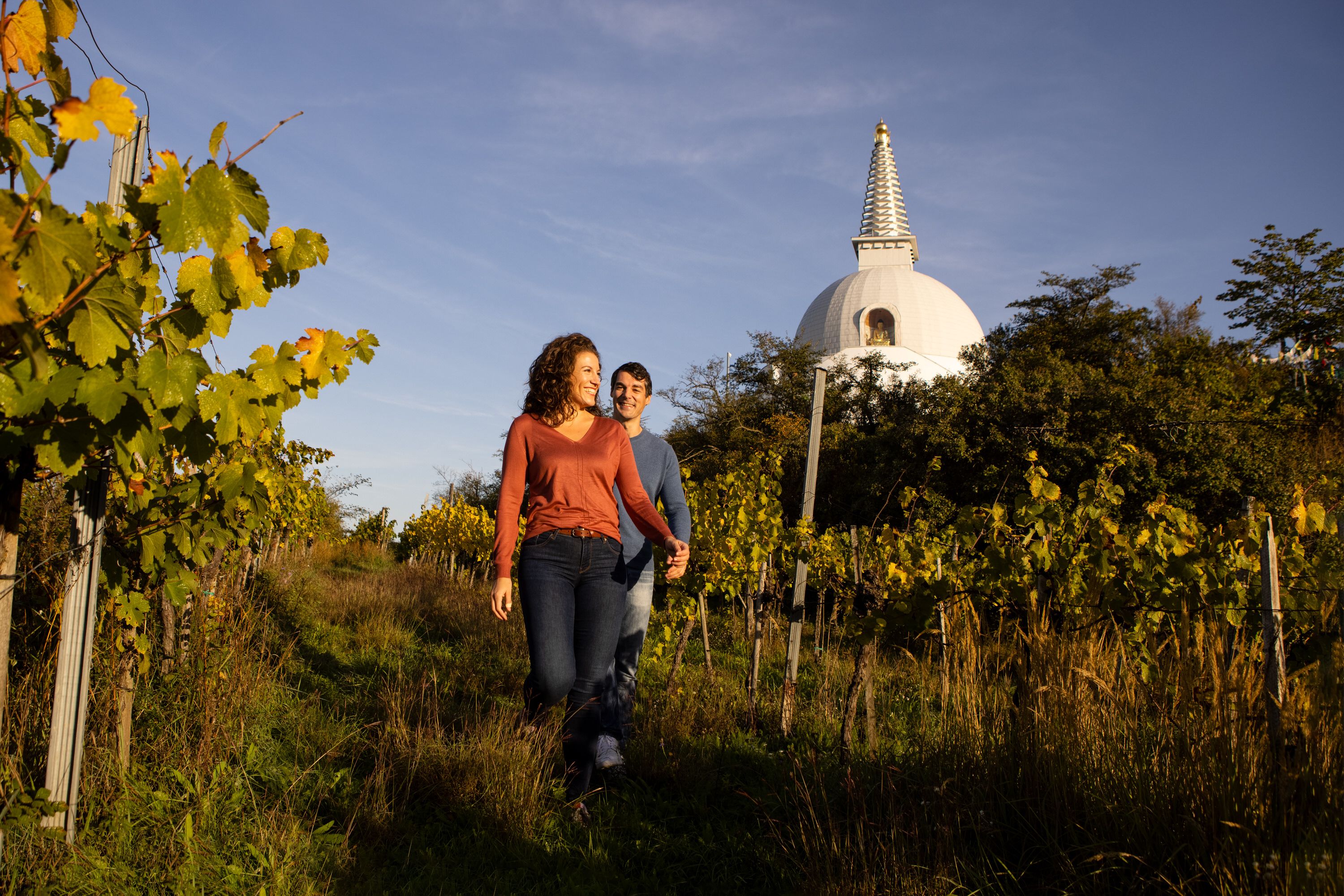 Pár prechádzajúci sa po viniciach, v pozadí stupa
