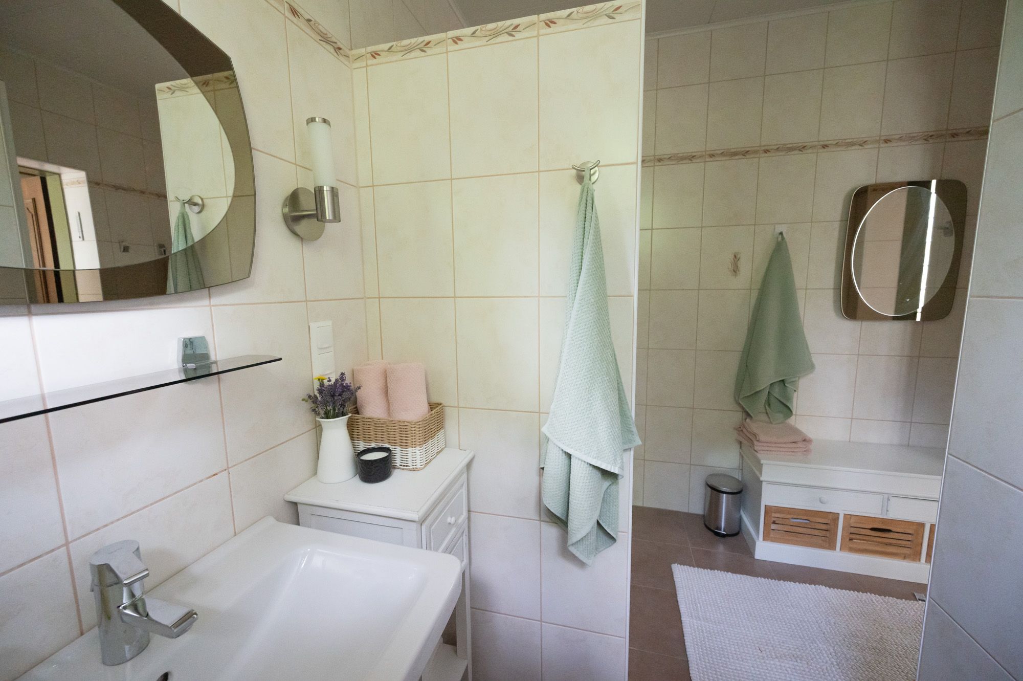 Moderná kúpeľňa s umývadlom, zrkadlom, uterákmi a dekoráciami.