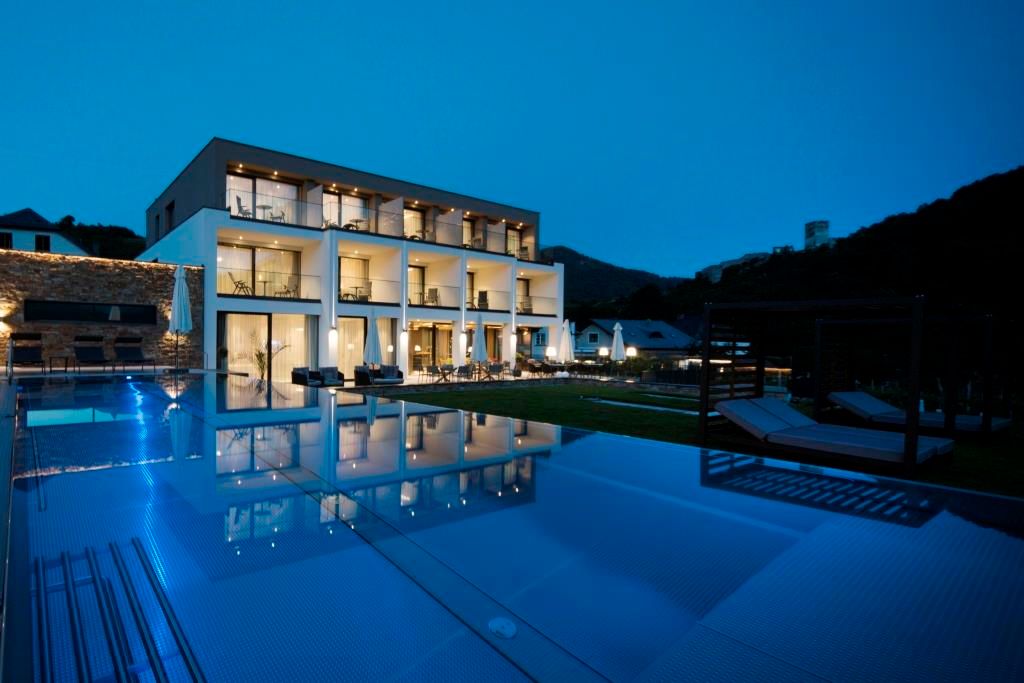 Moderný butikový hotel s nočným osvetlením bazéna.