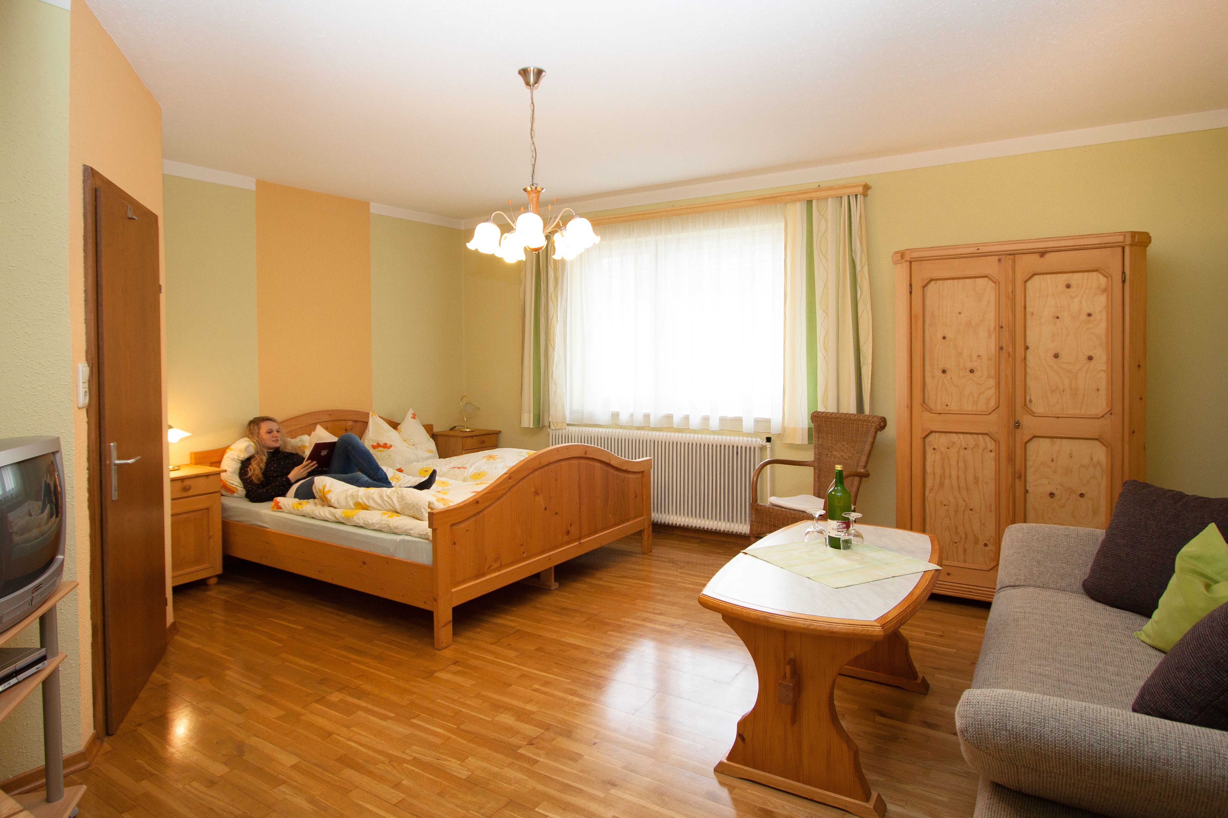 Útulná hotelová izba s dreveným nábytkom, posteľou, pohovkou a stolom.