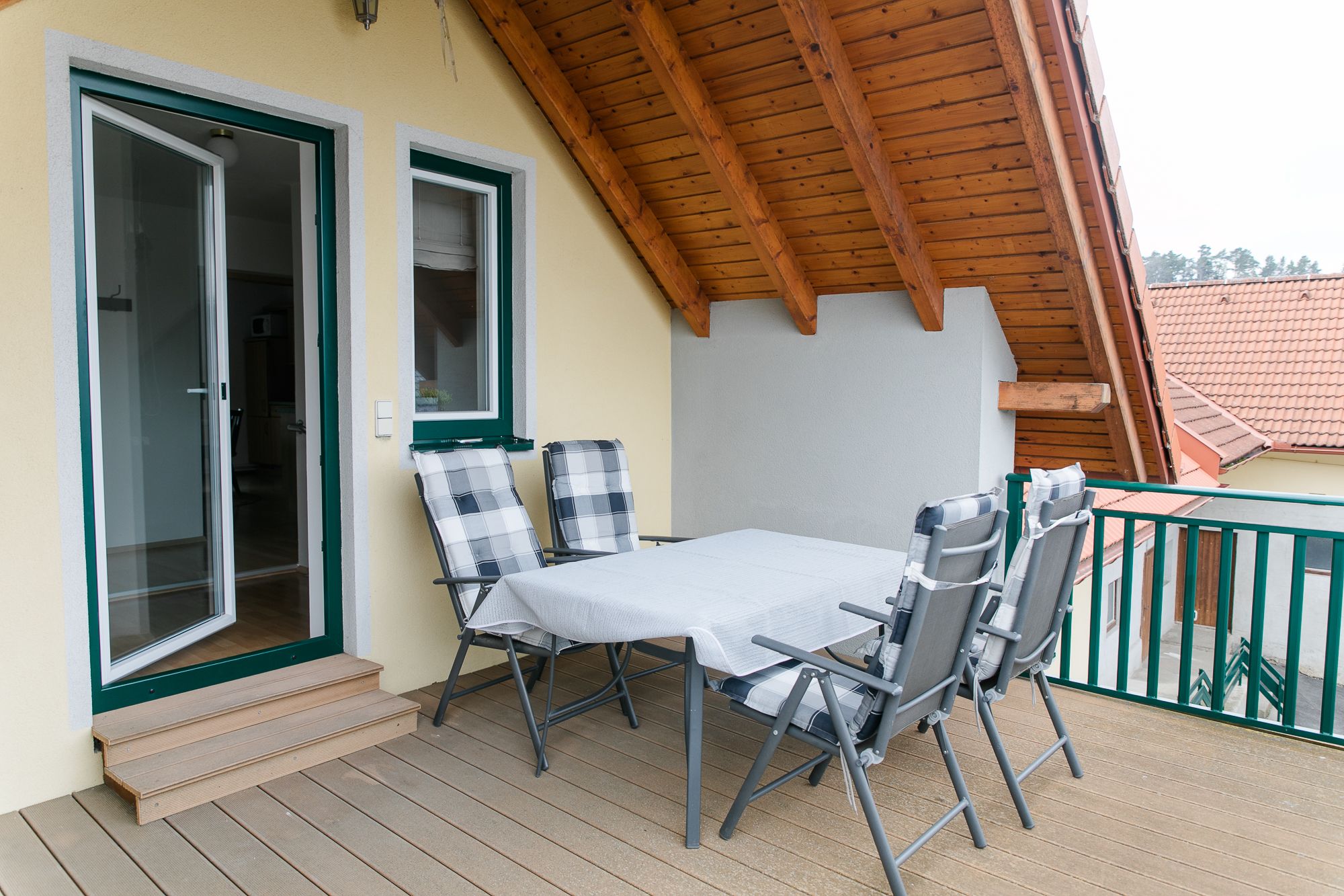 Strešná terasa so stolom a stoličkami pod drevenou strechou.