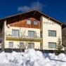 two-storey building with the inscription "Pension", Solapanelen and snow in front of the house, © Pension Klug