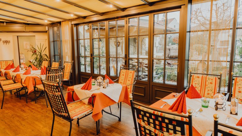 &Uacute;tuln&aacute; zimn&aacute; z&aacute;hrada so stolmi a stoličkami, obklopen&aacute; veľk&yacute;mi oknami s v&yacute;hľadom von.