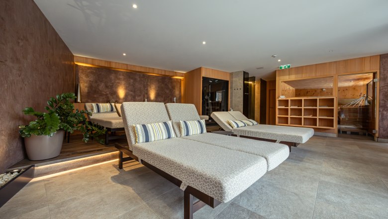 Pohľad do interiéru moderného wellness centra s ležadlami a rastlinami.