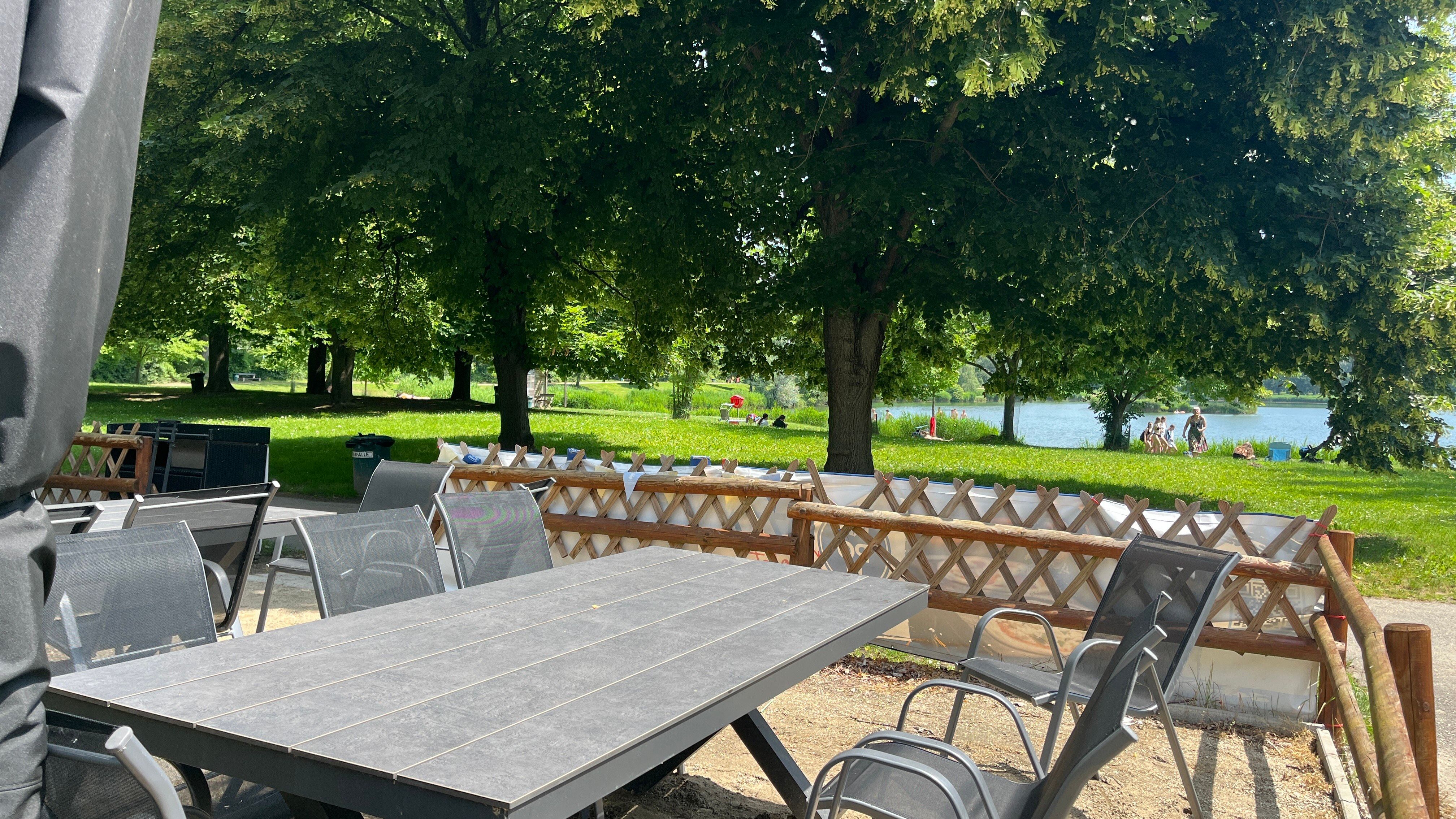 Záhradný stôl so záhradnými stoličkami, v pozadí bazén Tulln.