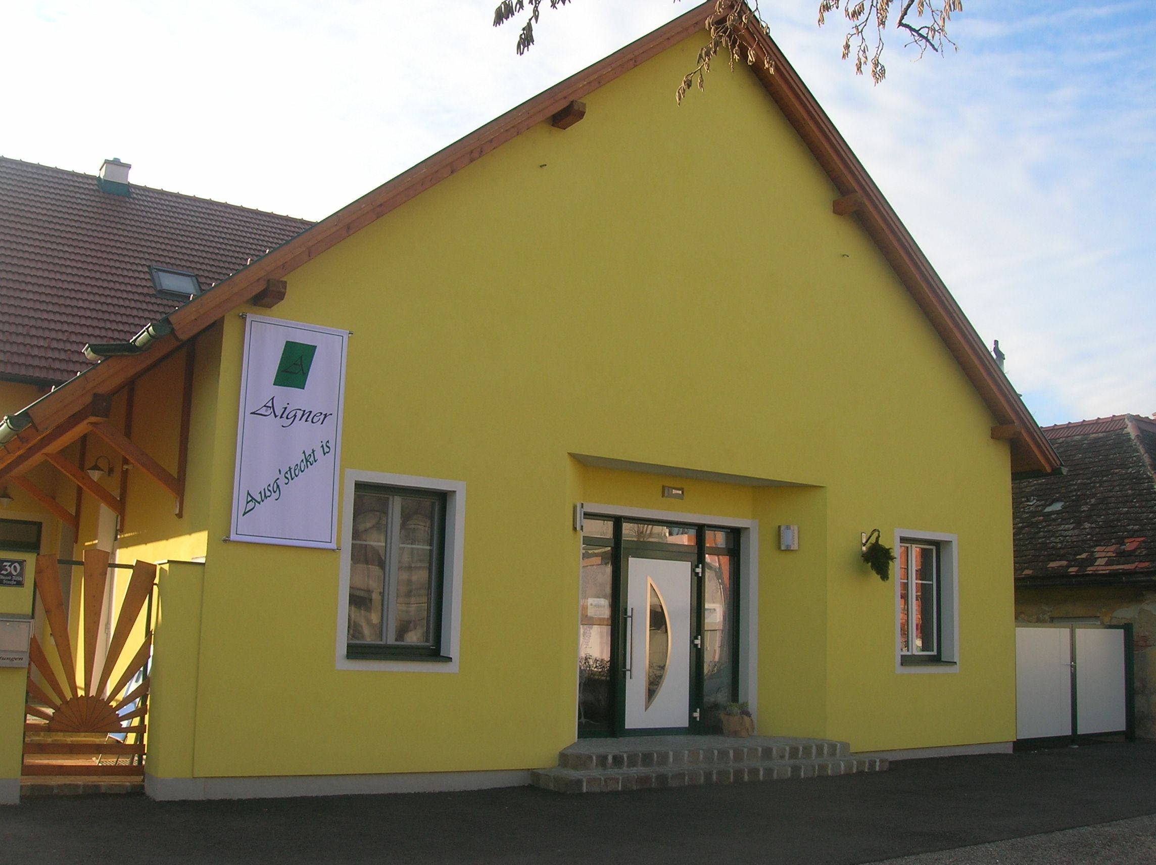 Žltá budova s nápisom "Aigner Ausg'steckt is" na fasáde.