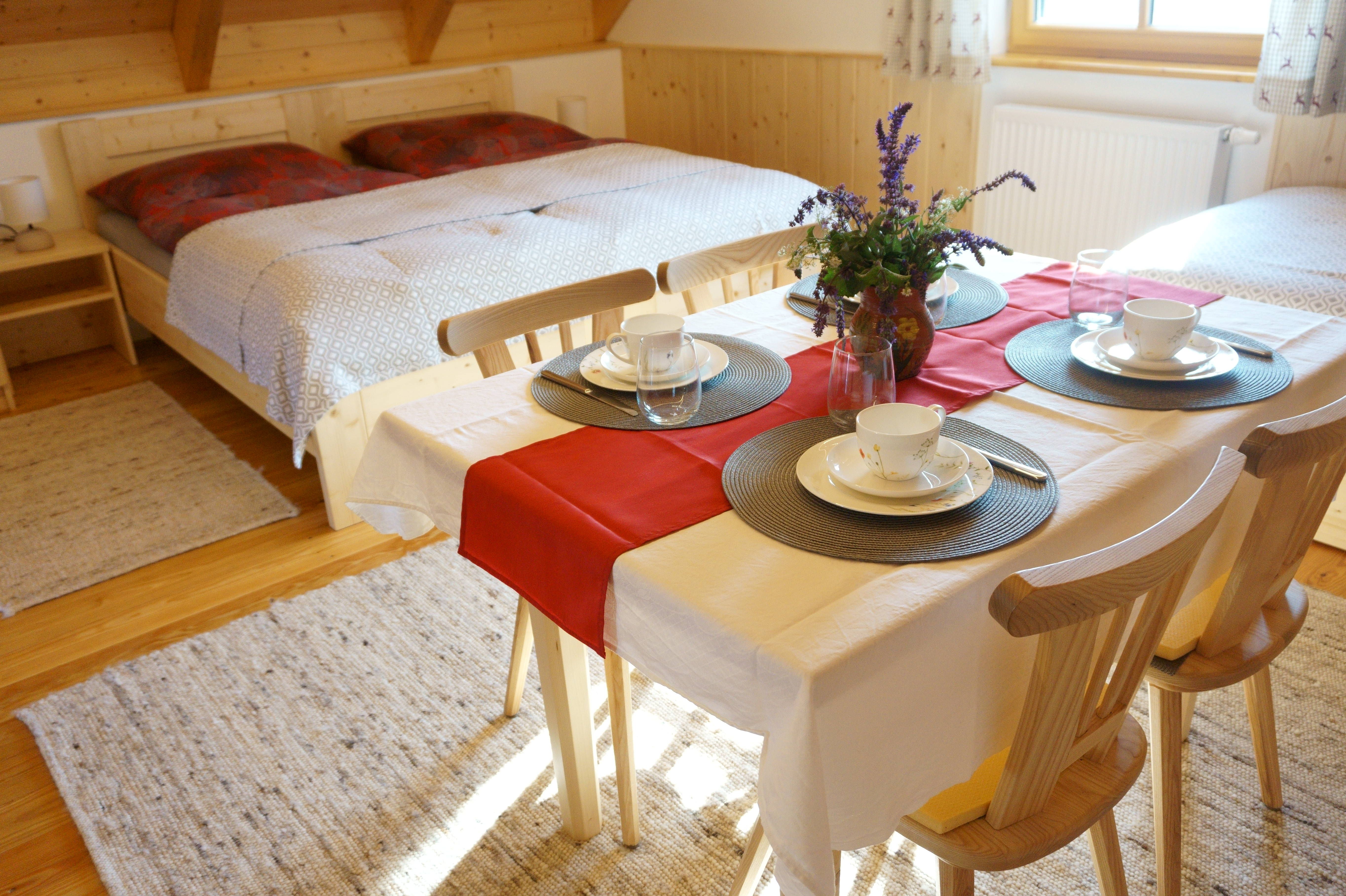 Útulná izba s manželskou posteľou a jedálenským stolom pre štyri osoby.