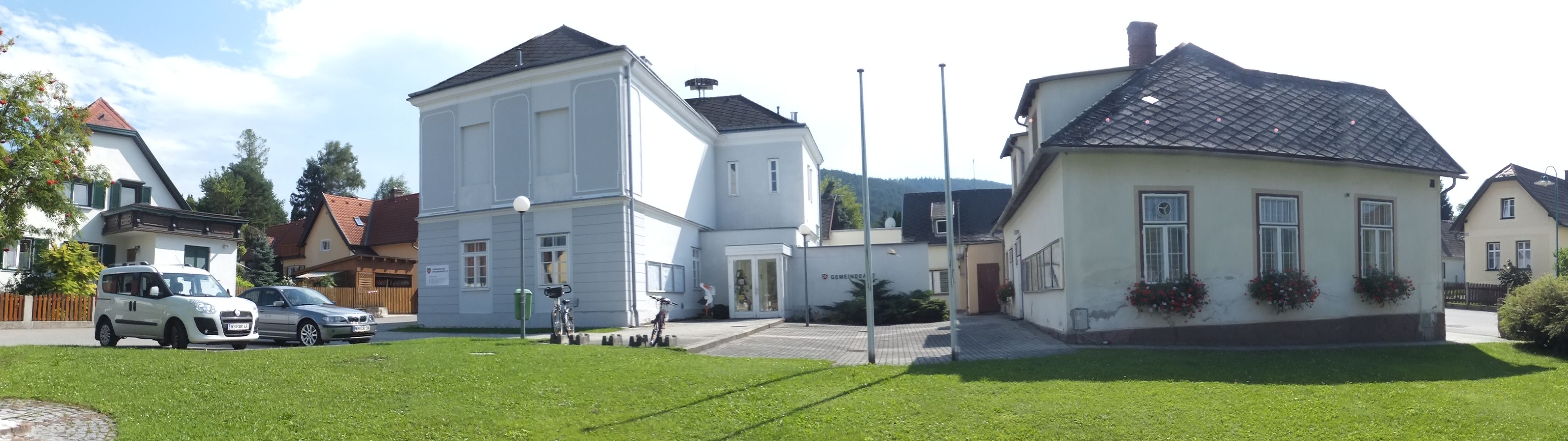 Panoramatická snímka obecného úradu vo Waidmannsfelde s okolitými budovami a autami.
