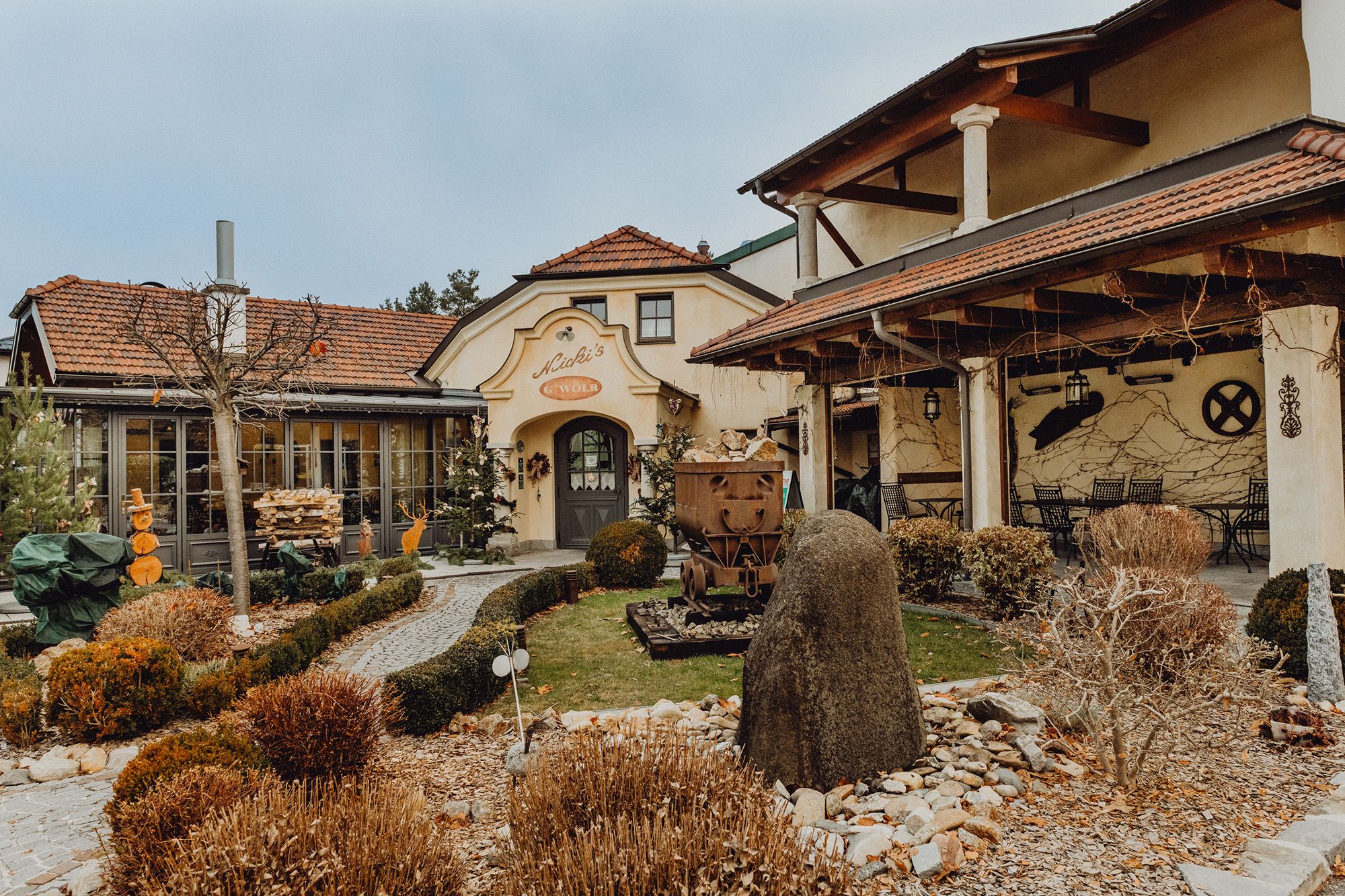 Exteriérový pohľad na tradičnú krčmu so záhradou a výzdobou.