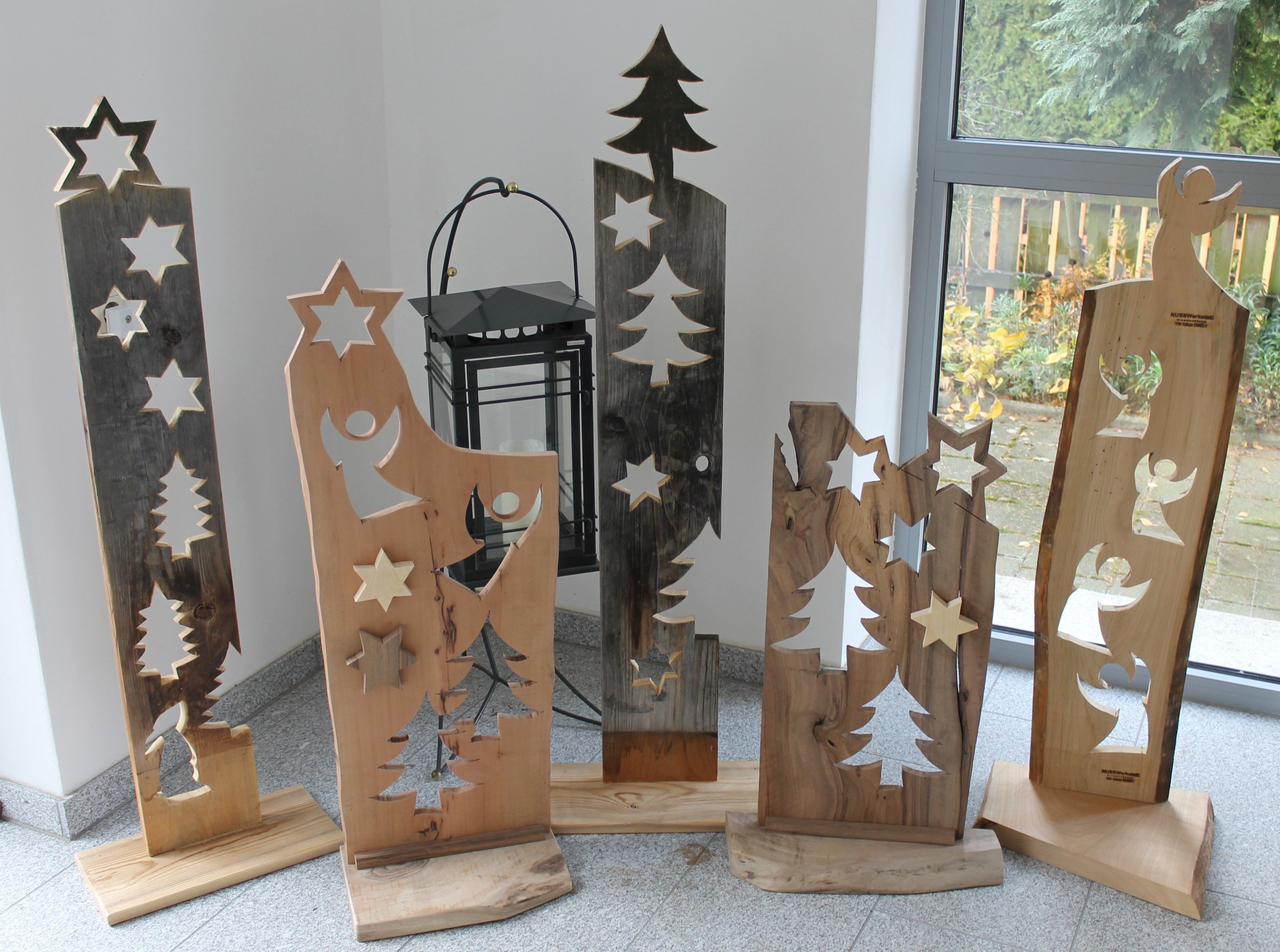 Drevené dekorácie s hviezdami a anjelmi pred oknom.